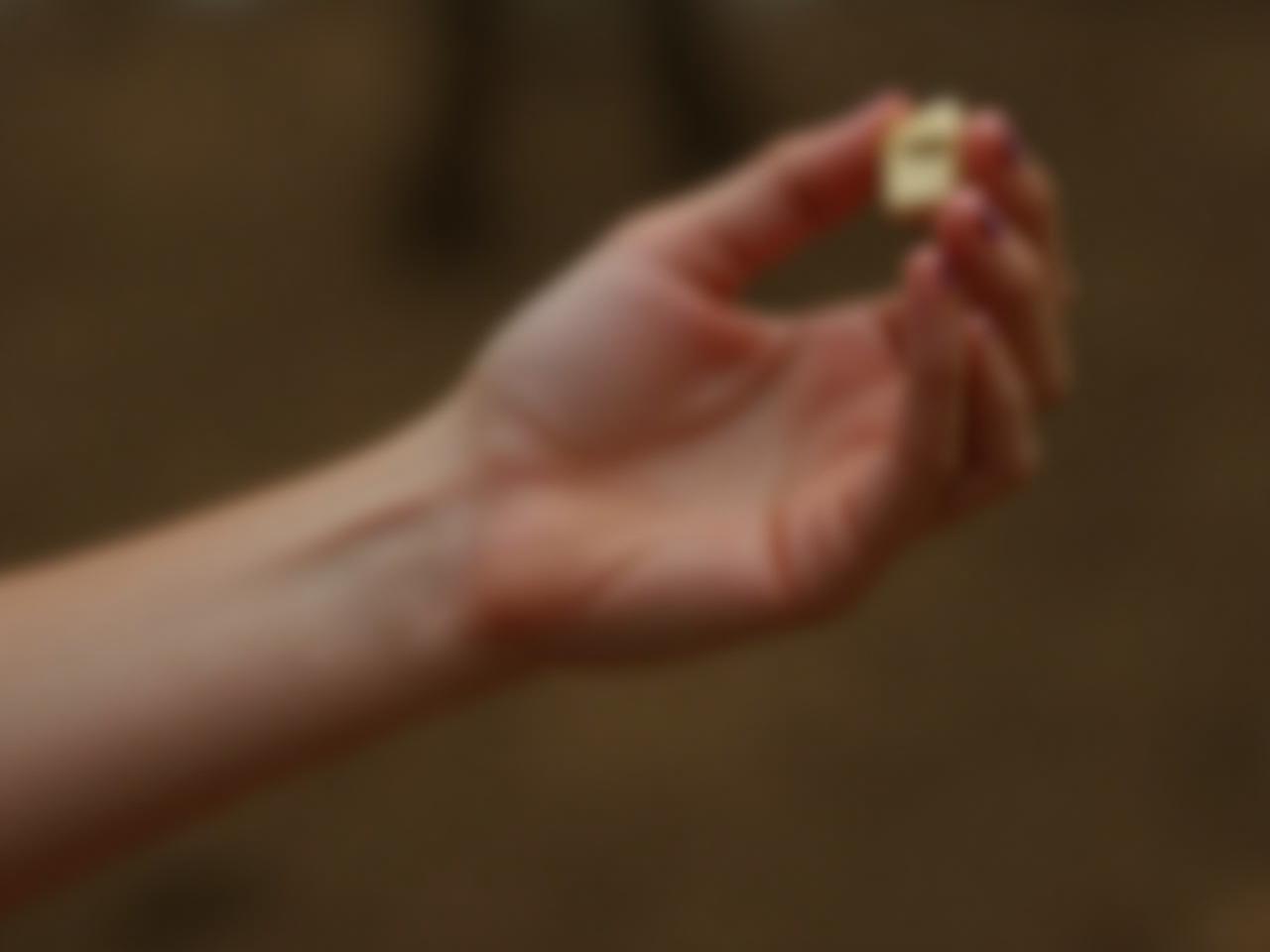 Close-up of a woman applying solid perfume on her wrist with a natural, earthy background.